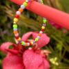 "Moomba" kinderarmbandje van Little Caribbean, versierd met kleurrijke kralen, gefotografeerd met kleurrijke bloemen op de achtergrond.