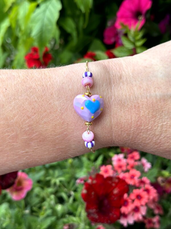 "Sea Hearts" armbandje van Little Caribbean met een hartvormig middelpunt en kleurrijke kralen, gedragen op een pols.